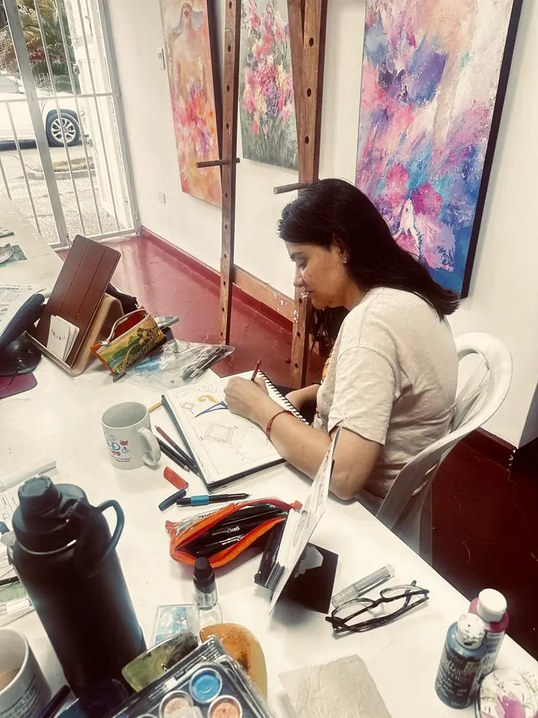 Mesa de trabajo del taller, rodeada de obras expuestas en la galería.