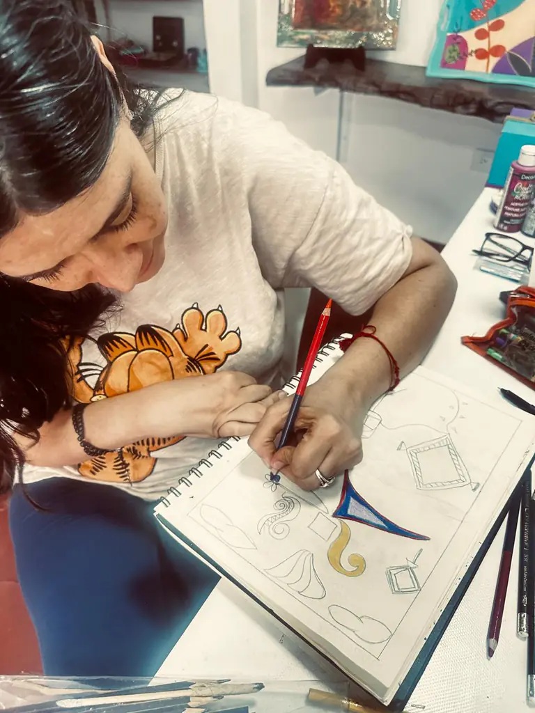 Detalle de una estudiante dibujando con lápices de color en su cuaderno.